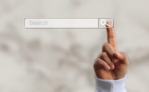 Ein Finger tippt auf eine digitale Suchleiste, als Symbol für die aktive Nutzung von Suchmaschinen und die Interaktion mit KI-Systemen.