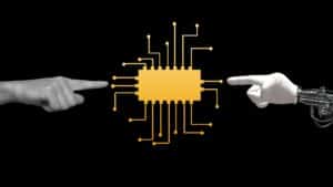 A human hand and a white robotic hand pointing at a yellow microchip with circuit tracks on a black background.